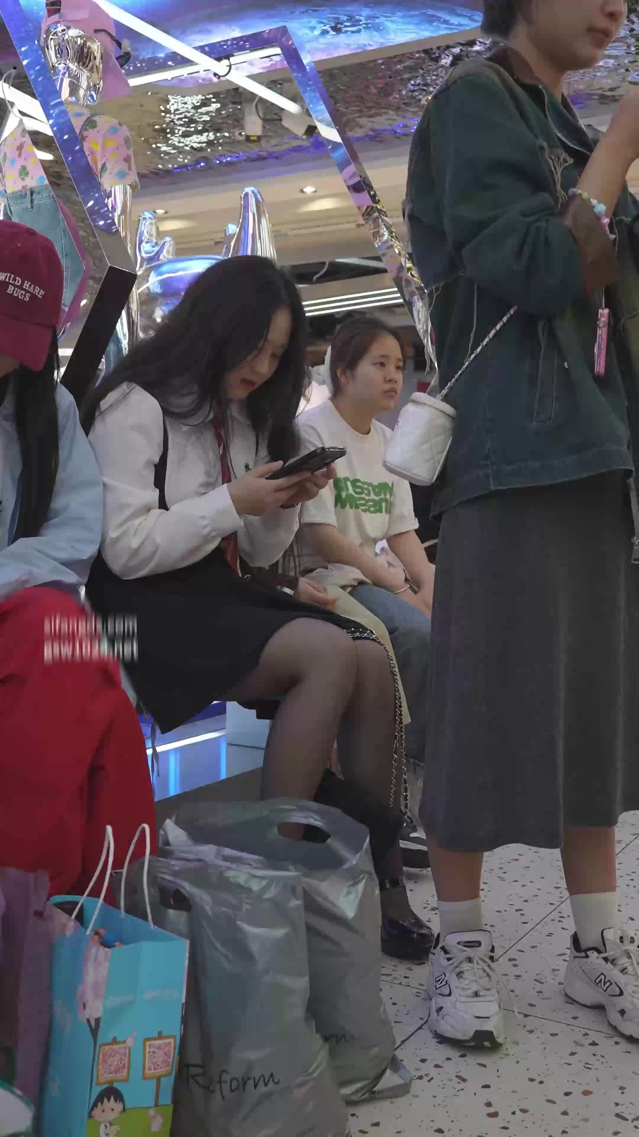 붐비는 공간에 흰색 바지를 입은 귀엽고 뚱뚱한 교복 소녀가 있습니다.